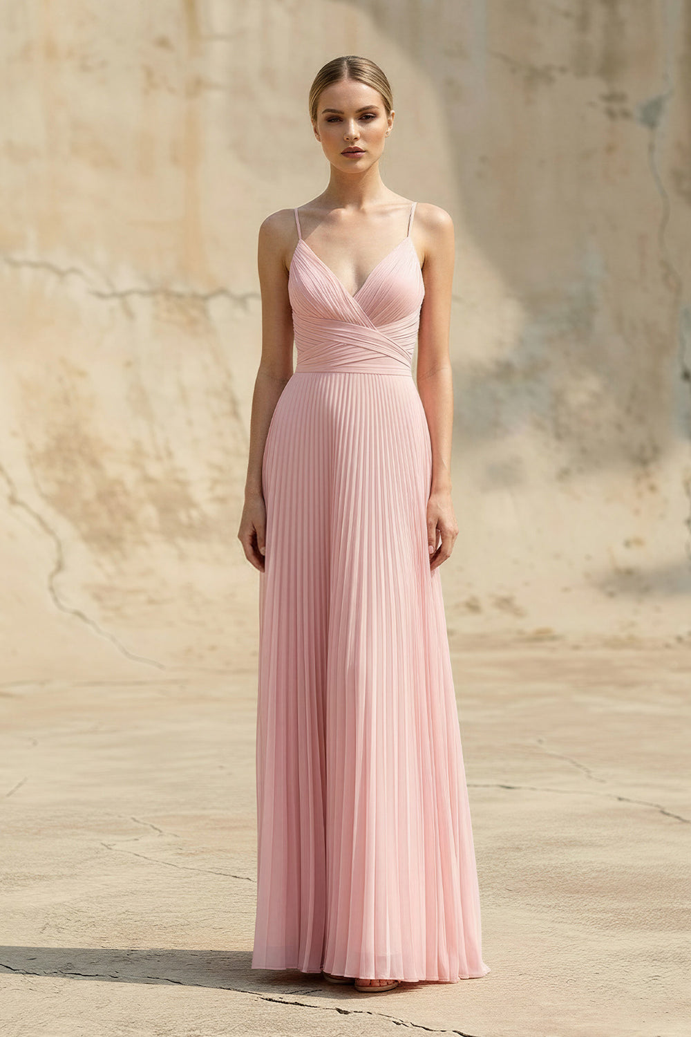 Woman wearing a pink pleated dress against a stone wall background