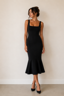 Woman wearing a black dress against a plain background